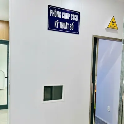Cửa phòng có biển Phòng chụp CTCB kỹ thuật số và biển cảnh báo tia X